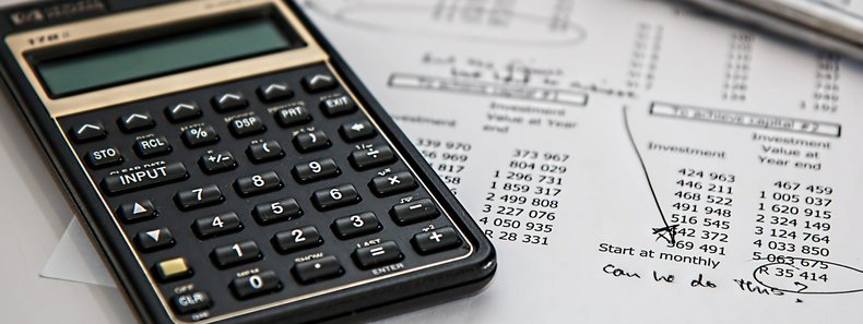 Ein Taschenrechner, ein Stift und ein Papier mit Statistiken liegen auf einem Tisch.