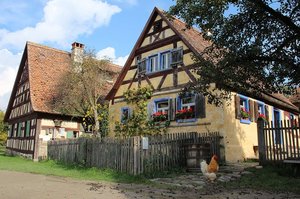 Zwei alte Fachwerkhäuser-Bauernhäuser im Freilandmuseum, sie sind umgeben von Bauerngärten, der Himmel ist blau. 