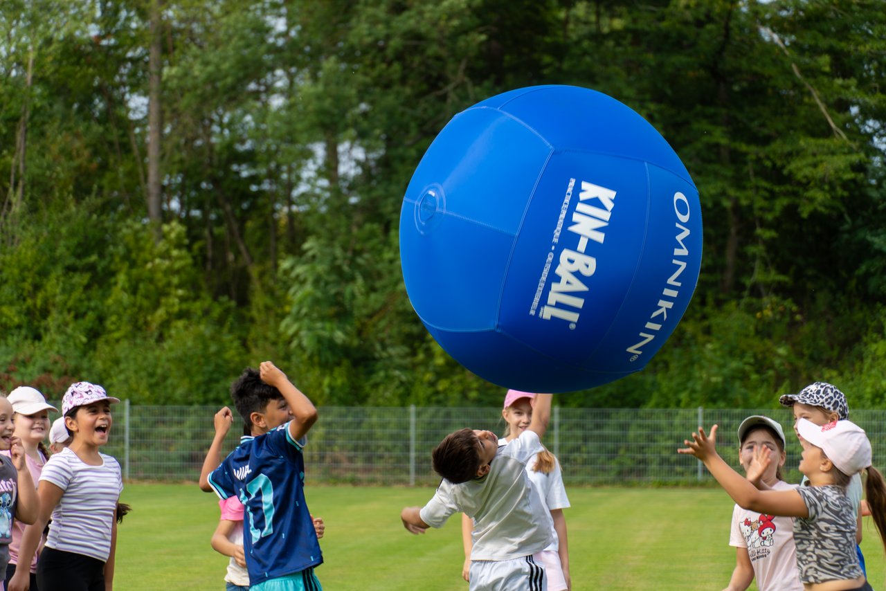 Viele Kinder sind an der Station "Kin-Ball" im Einsatz und schlagen gegen einen überdimensionalen aufgeblasenen Ball.