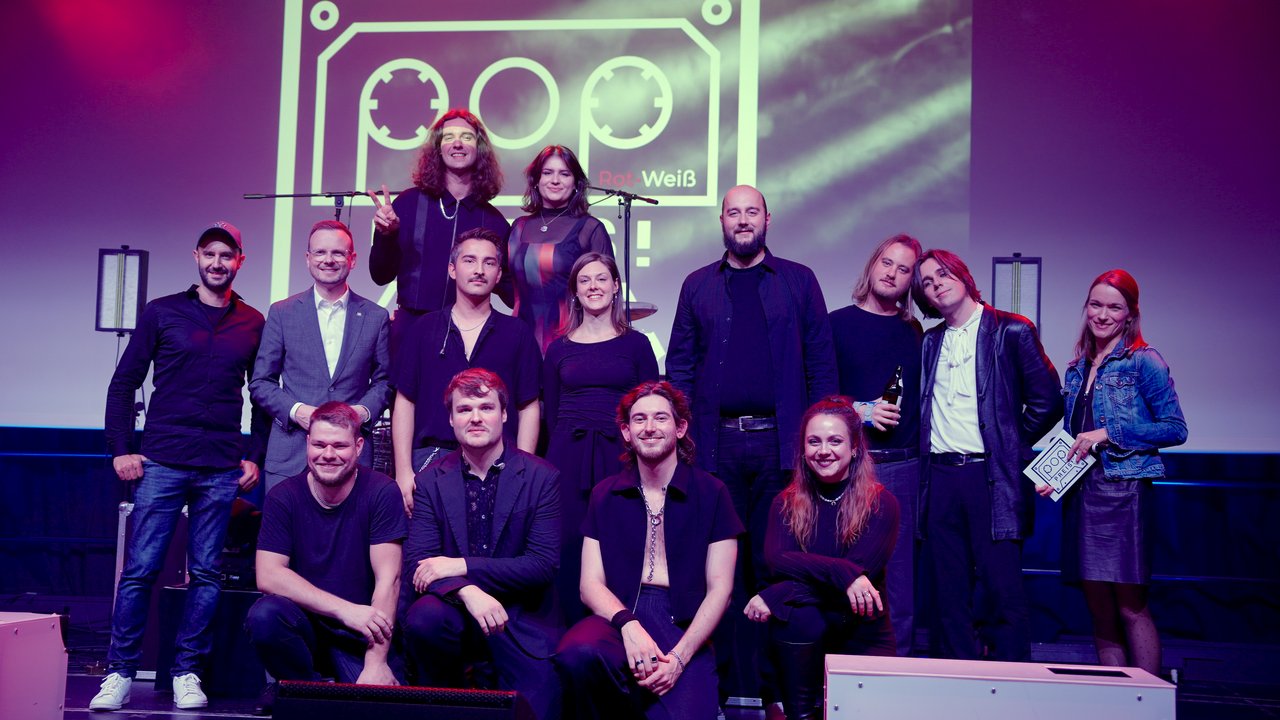 Gruppenbild der Preisträger, Bezirkstagspräsident Peter Daniel Forster und Popularmusikberater Andy Horst auf der Bühne.