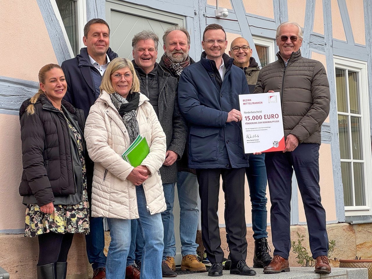 Gruppenfoto bei der Übergabe des Förderbescheids vor dem sanierten Gebäude.