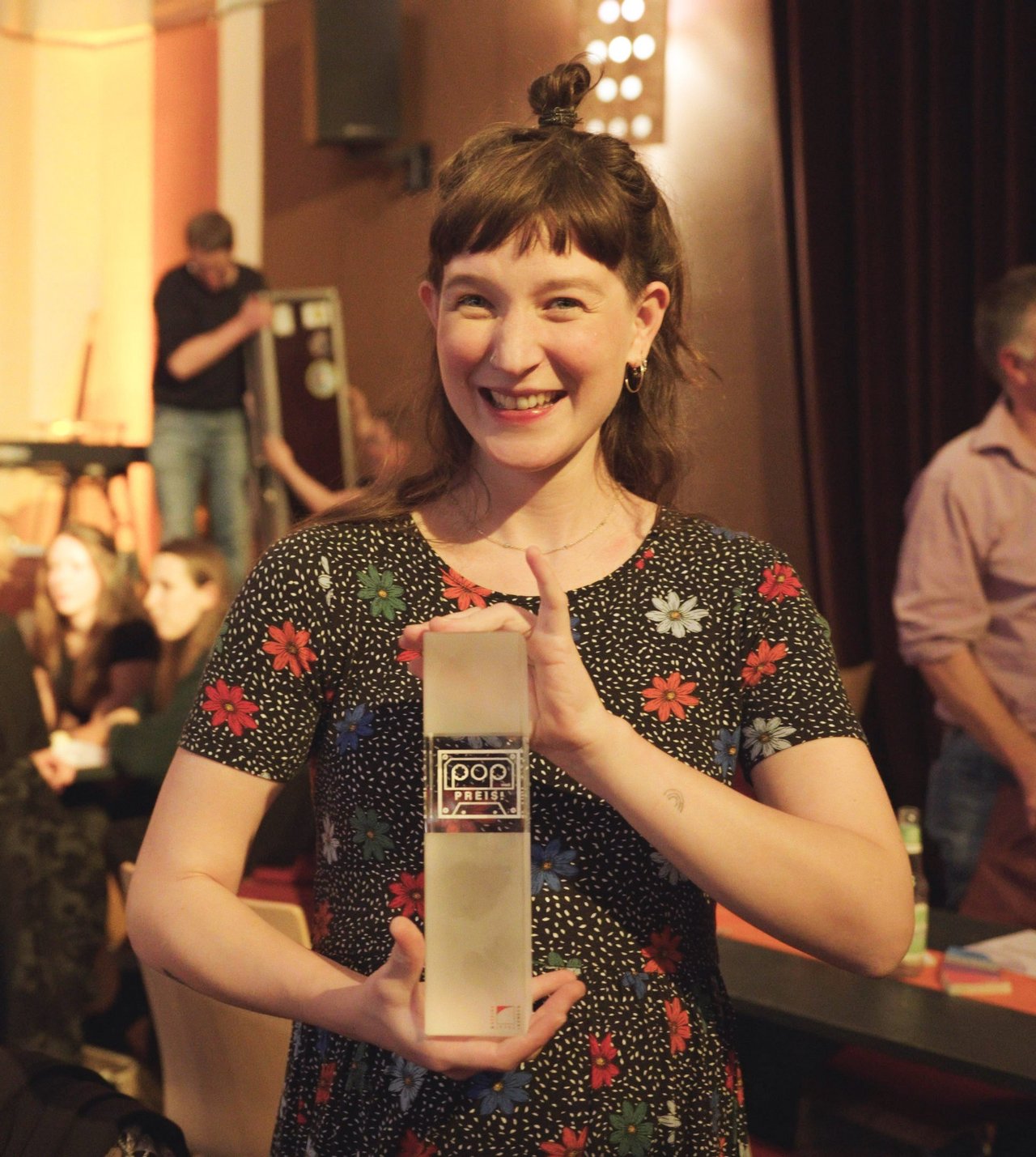 Maleen Schulz-Kallenbach hält den Pop-Preis in der Hand und lächelt in die Kamera