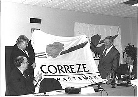 Der damalige Bezirkstagspräsident Gerd Lohwasser und der damalige Präsident der Corrèze Dr. Jean-Pierre Dupont halten eine Fahne der Corrèze nach Unterzeichnung der Partnerschaftsurkunde in Frankreich hoch.
