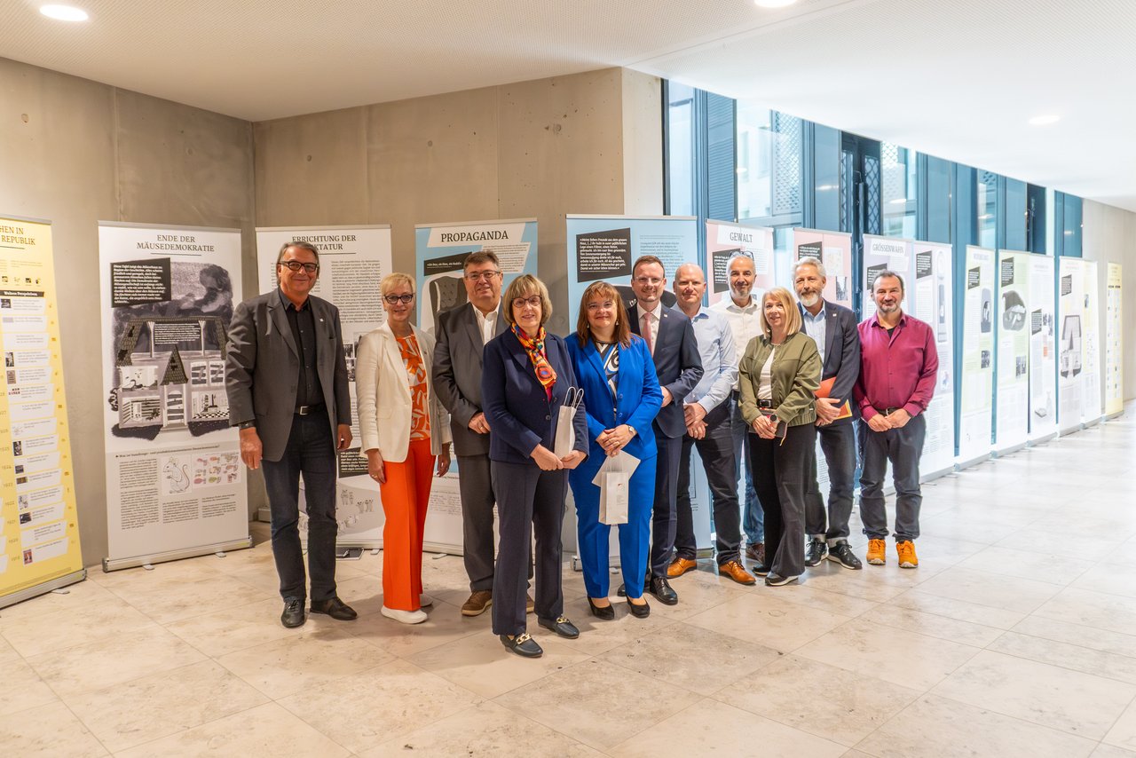 Menschengruppe steht vor Ausstellungsplakaten