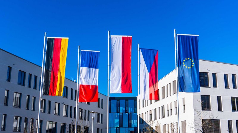 Die deutsche, französische, polnische, tschechische und europäische Flagge hängen nebeneinander an Fahnenmasten.