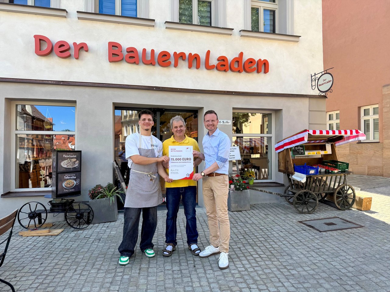 Gruppenfoto vor dem Bauernladen mit der Urkunde in der Hand.