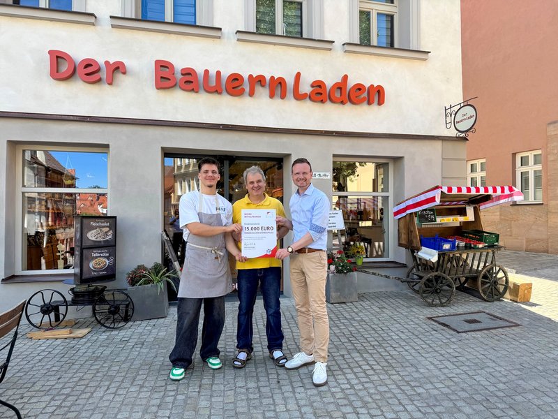 Gruppenfoto vor dem Bauernladen mit der Urkunde in der Hand.