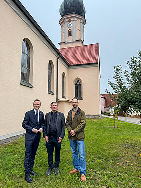Drei Männer stehen vor einer Kirche