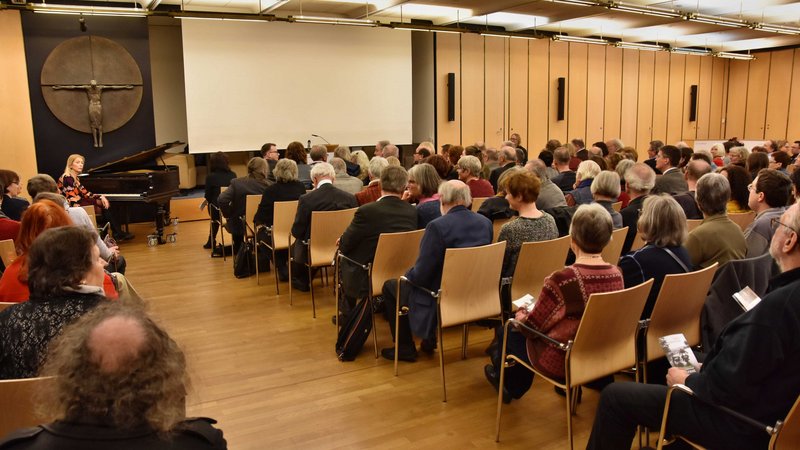 Ein voll gefüllter Saal. Das Publikum sitzt auf Stühlen und wartet, dass es auf der Bühne losgeht.
