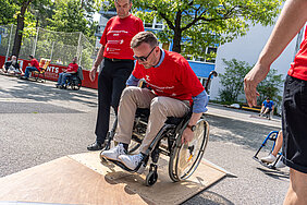 Bezirkstagspräsident Peter Daniel Forster in einem Rollstuhl im Rollstuhlparcours.