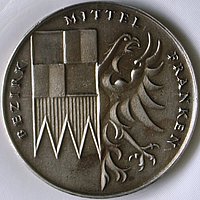 Die Bezirksmedaille hat die Form einer Münze und trägt auf der Vorderseite das Wappen des Bezirks Mittelfranken mit der Umschrift: Bezirk Mittelfranken.