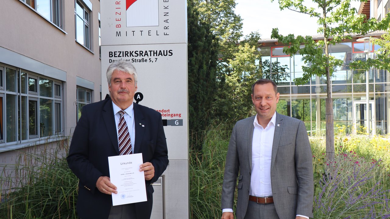 Jürgen Müller (links) mit Bezirkstagspräsident Armin Kroder (rechts) vor dem Bezirksrathaus in Ansbach.