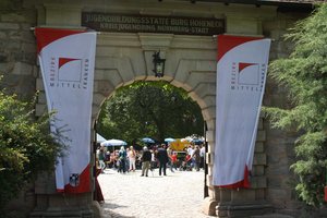 Blick auf das Burgtor der Burg Hoheneck. Rechts und links neben dem Eingang hängen Fahnen des Bezirks Mittelfranken.