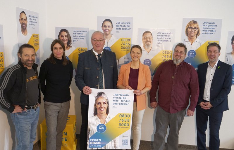 Gruppenbild der aufgelisteten Personen vor Plakaten.