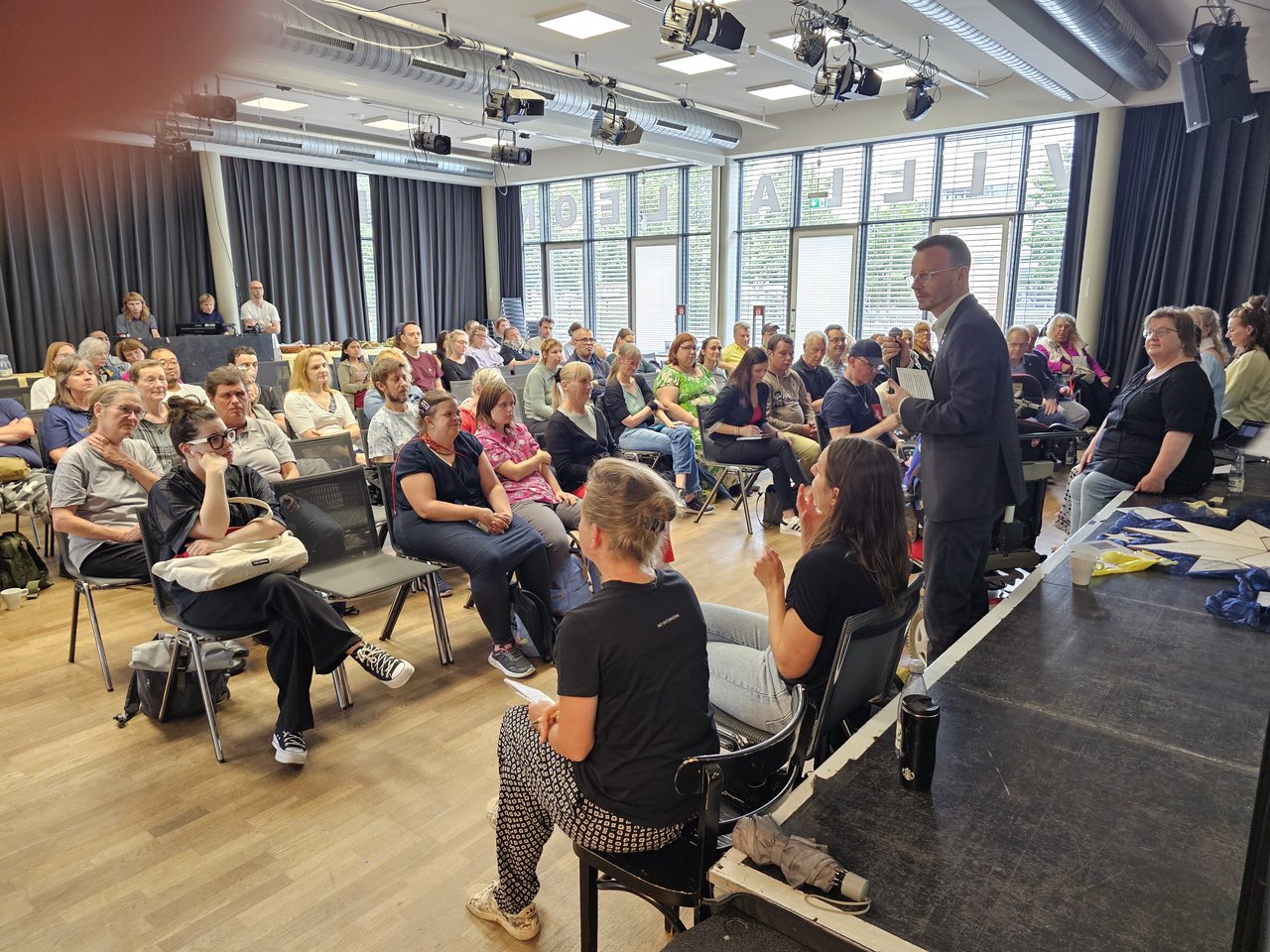Peter Daniel Forster steht vor einem sitzenden Publikum und spricht.