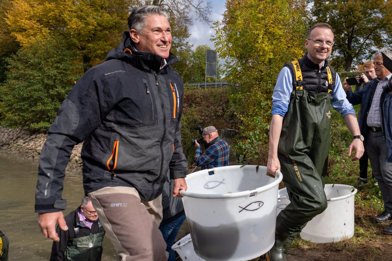 Zwei Männer tragen Fische im Eimer