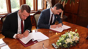 Bezirkstagspräsident Kroder und Kreishauptmann Grolich unterzeichnen die Partnerschaftsurkunde.
