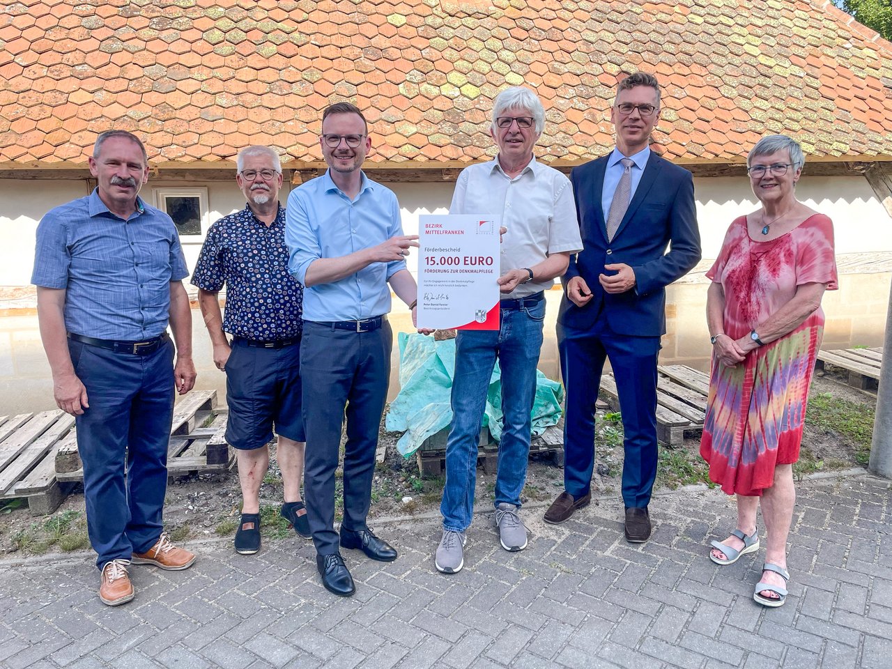 Bezirkstagspräsident Peter Daniel Forster (3. v. l.) überreicht den Förderbescheid des Bezirks Mittelfranken an Dr. Herbert May (4. v. l.), den Vorsitzenden des Nürnberger Bauernhausfreunde e. V.