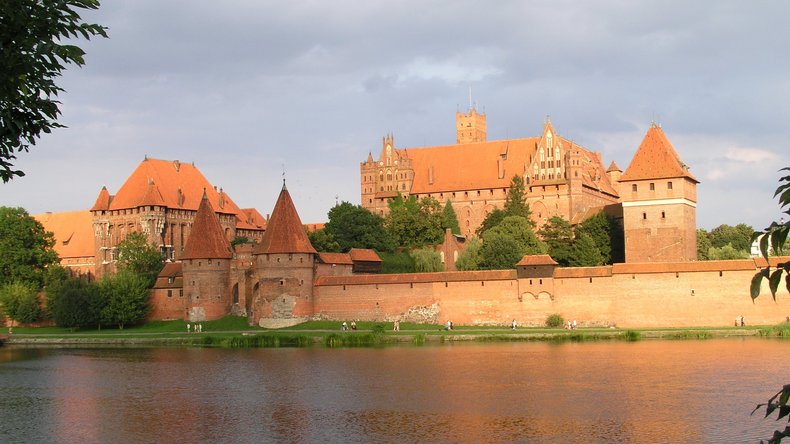 Aufnahme der Marienburg in Pommern. Davor fließt ein Fluss dabei.