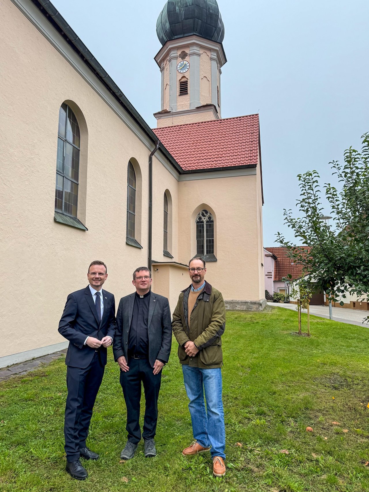 Drei Männer stehen vor einer Kirche